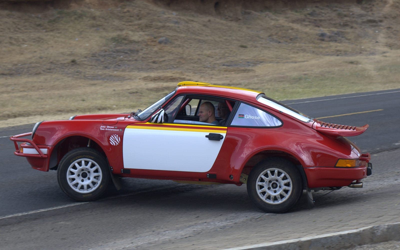 The Safari car at speed in side profile on a test road, driver visible at the wheel
