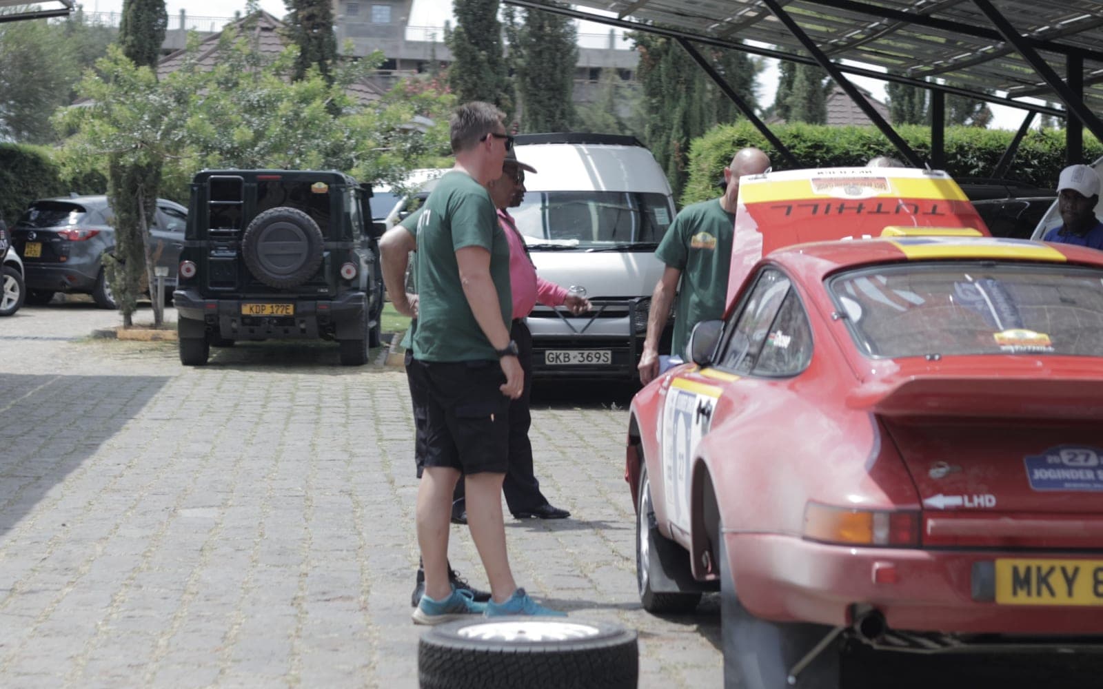 The crew going over the car at the end of the day, spare wheel out, everyone around the back of the car