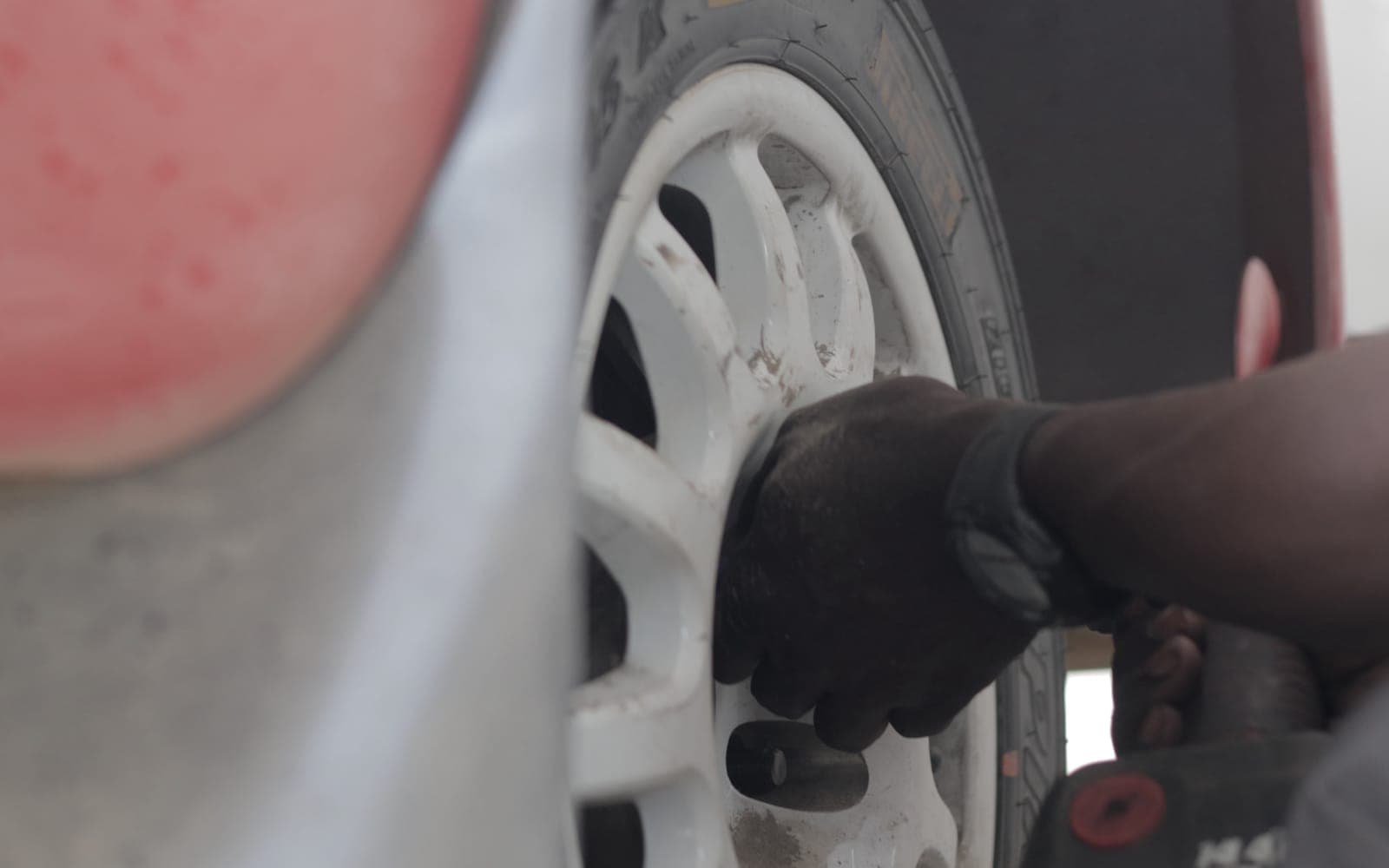 Gloved hands on the wheel nuts mid wheel-change, close up